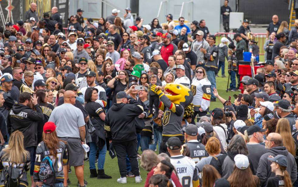 Chance the Gila Monster holds a baby dressed in team gear up to the crowd during the Vegas Gold ...