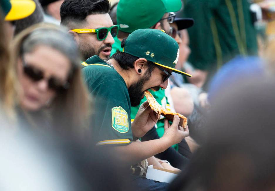 An Oakland Athletics fan enjoys a piece of pizza during a Major League Baseball game with the C ...