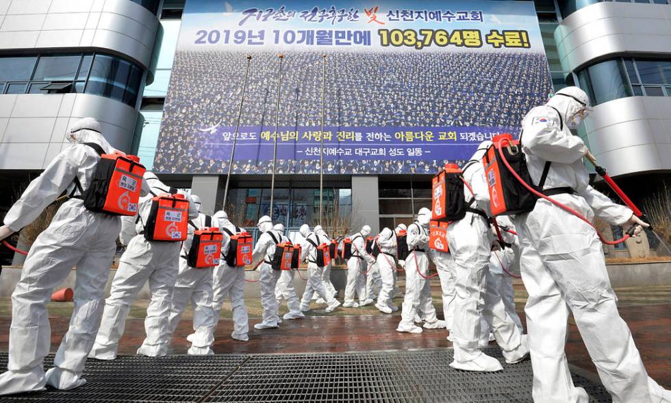 Army soldiers wearing protective suits spray disinfectant to prevent the spread of the coronavi ...