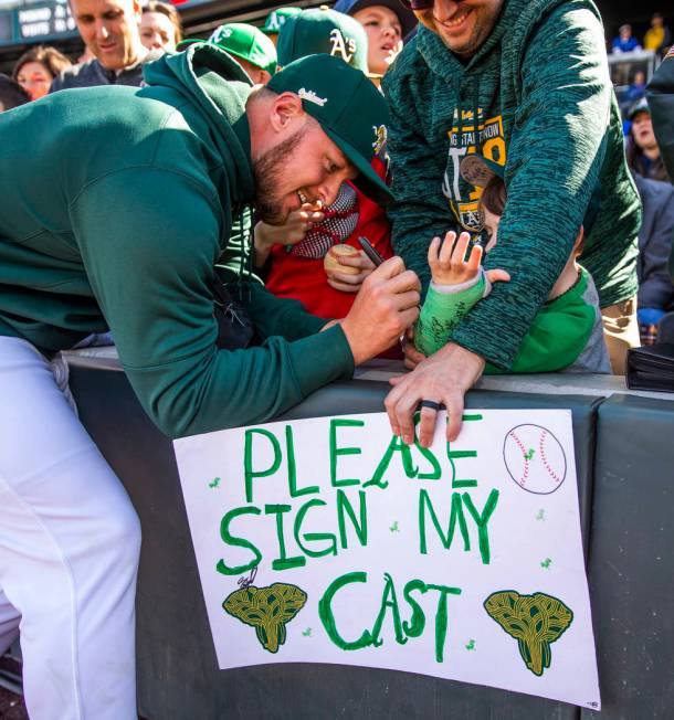 Oakland Athletics pitcher J.B. Wendelken signs the cast of Charleston Kenton, 6, joined by his ...