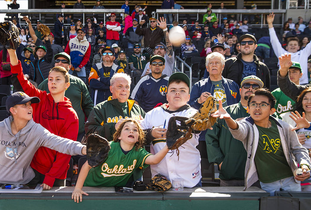Fans work for position to catch a ball tossed by an Oakland Athletics player during a Big Leagu ...