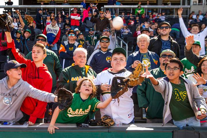 Fans work for position to catch a ball tossed by an Oakland Athletics player during a Big Leagu ...