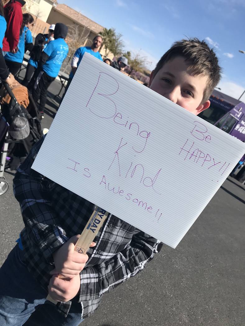 Phoenix Merle holds up a sign he made. It says, "Being kind is awesome!!" Merle took part in th ...