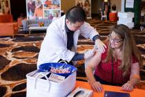 Vons Pharmacy intern Kevin Chang cleans Brenda Julian's upper arm in preparation for a flu shot ...