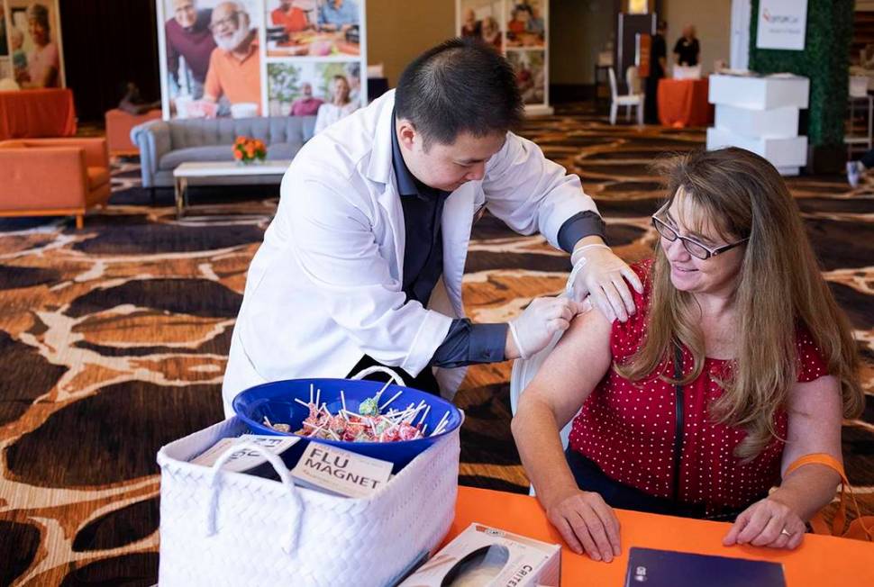 Vons Pharmacy intern Kevin Chang cleans Brenda Julian's upper arm in preparation for a flu shot ...