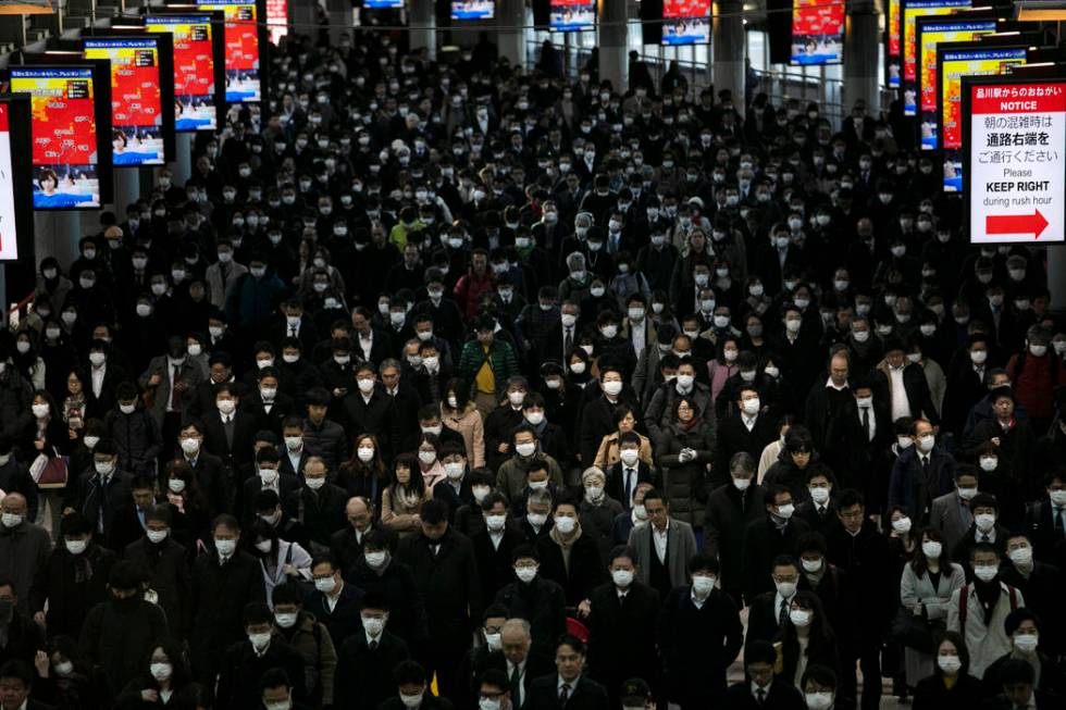 A large crowd wearing masks commutes through Shinagawa Station in Tokyo, Tuesday, March 3, 2020 ...