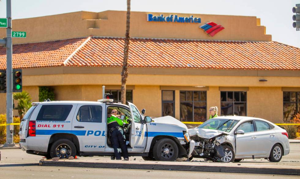 An investigations team works the accident scene where a Henderson Police vehicle was struck whi ...