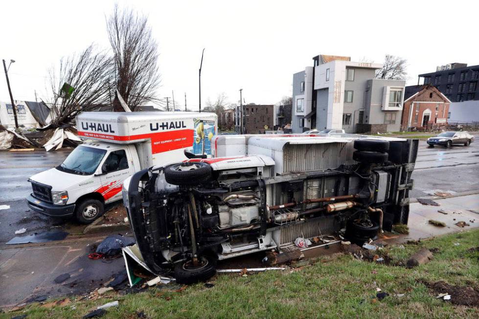 Damaged trucks sit on a sidewalk as well as the street following a deadly tornado, Tuesday, Mar ...