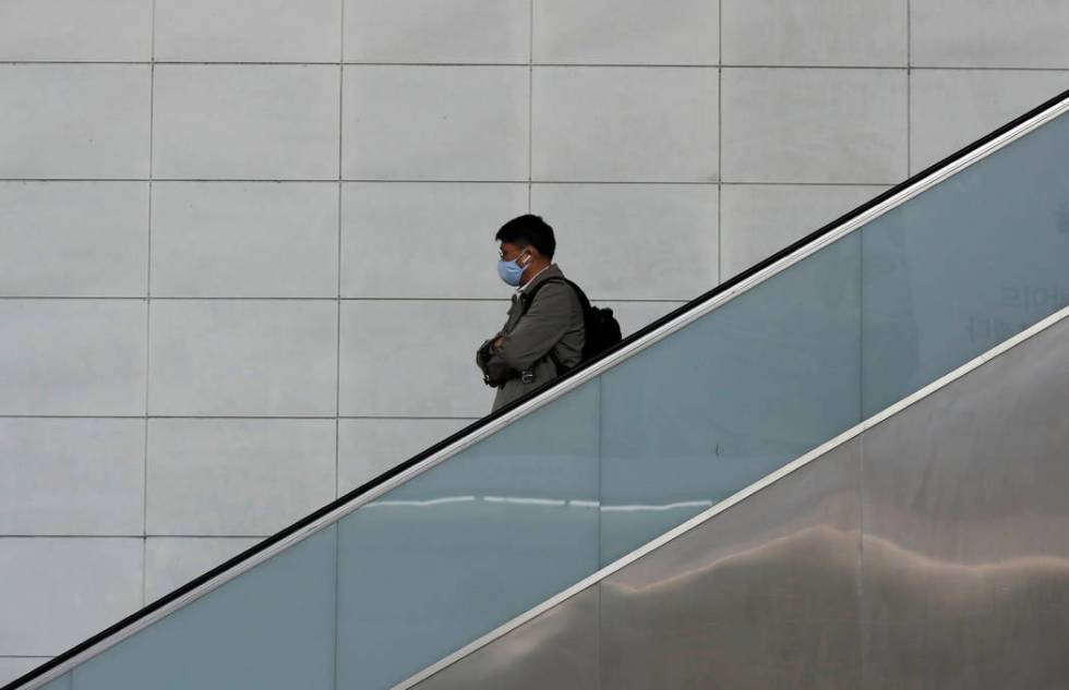 A man wearing a face mask rides the escalator in Seoul, South Korea, Wednesday, March 4, 2020. ...