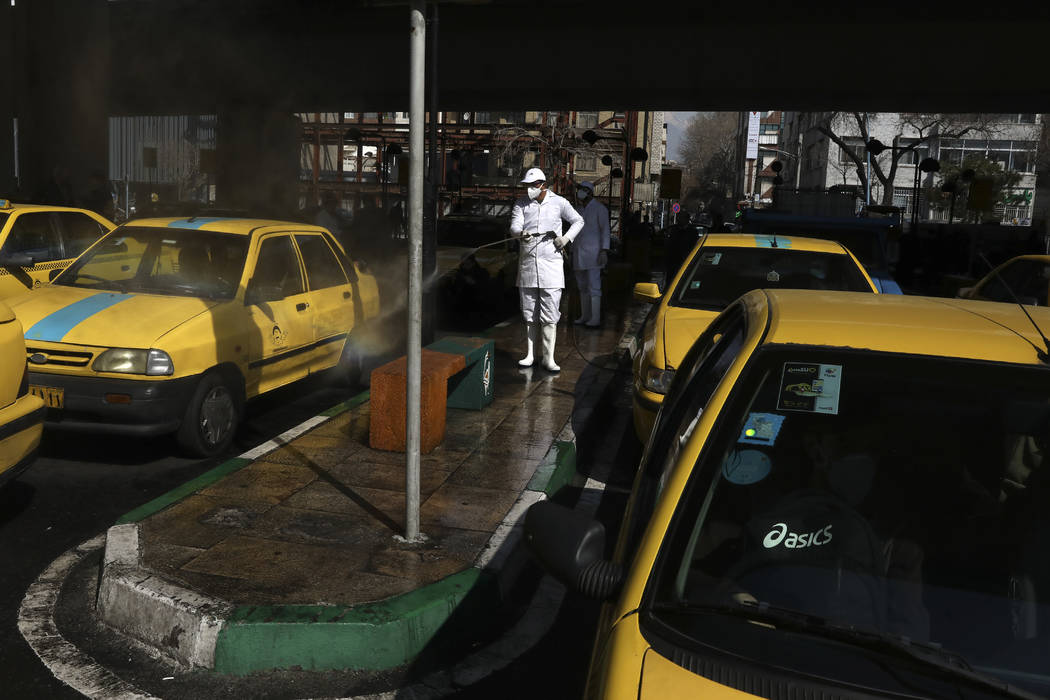 A city worker disinfects a taxi because of the new coronavirus, in Tehran, Iran, Thursday, Marc ...
