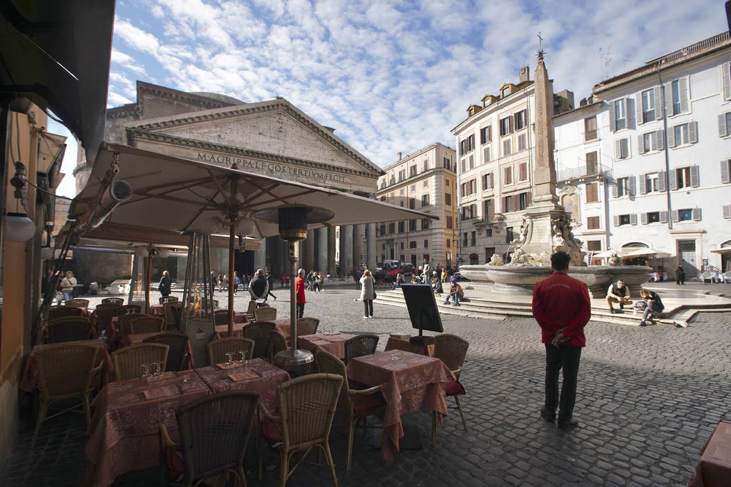 Waiters wait for customers outside a restaurant next to the Pantheon, in Rome, Thursday, March ...