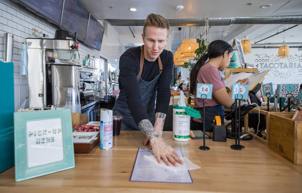 Bar tender David Denk disinfects menus at Tacotarian in the Arts District in Las Vegas on Thurs ...