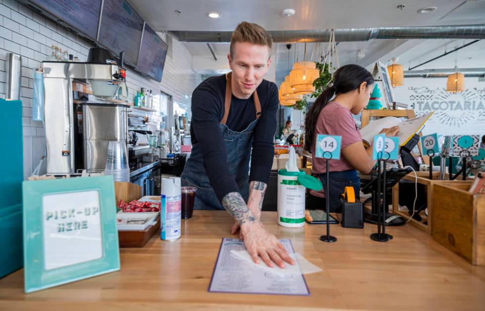 Bar tender David Denk disinfects menus at Tacotarian in the Arts District in Las Vegas on Thurs ...