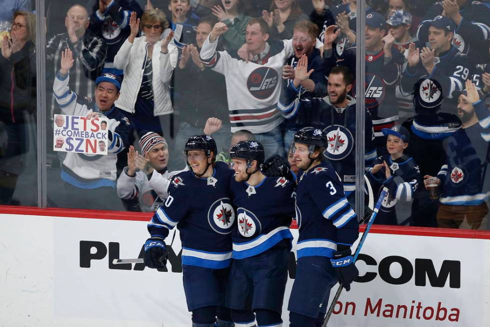 Winnipeg Jets' Cody Eakin (20), Nikolaj Ehlers (27) and Tucker Poolman (3) celebrate Ehlers' go ...