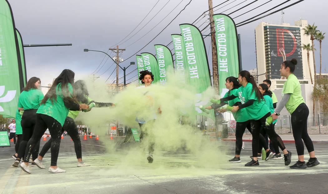 A runner is covered in green powder as he makes his way through one of several Color Run colori ...