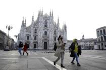 A woman wearing a sanitary mask walks past the Duomo gothic cathedral in Milan, Italy, in Febru ...