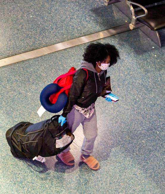 A passenger wears a face mask while walking through the Terminal 1 baggage claim in McCarran In ...