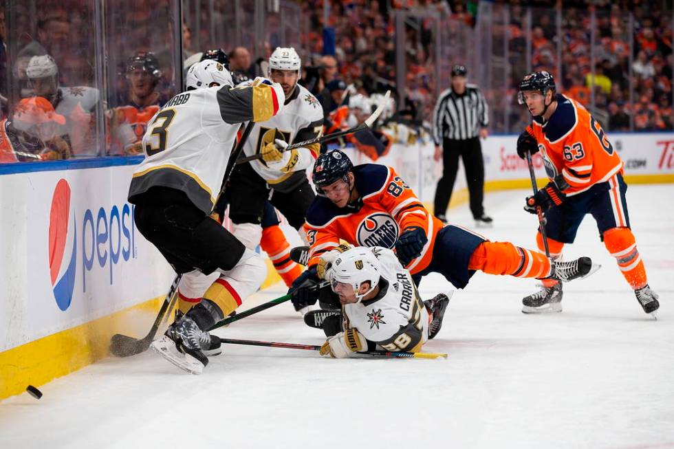 Edmonton Oilers' Matt Benning (83) falls on top of Vegas Golden Knights' William Carrier (28) d ...