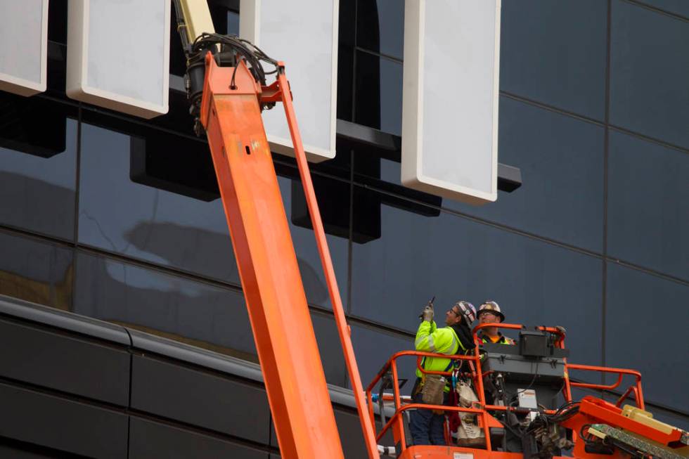 A worker takes a photo after helping install the last letter in the signage for the Raiders All ...