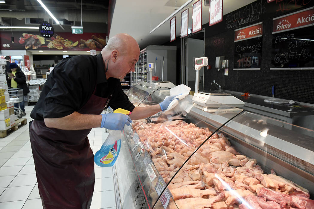 An employee disinfects the glass cover of a butcher counter to prevent the spread of the novel ...