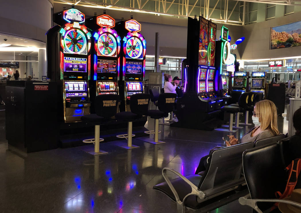 A passenger wearing a mask, right, sits about one of the near empty slot machine areas in Conco ...