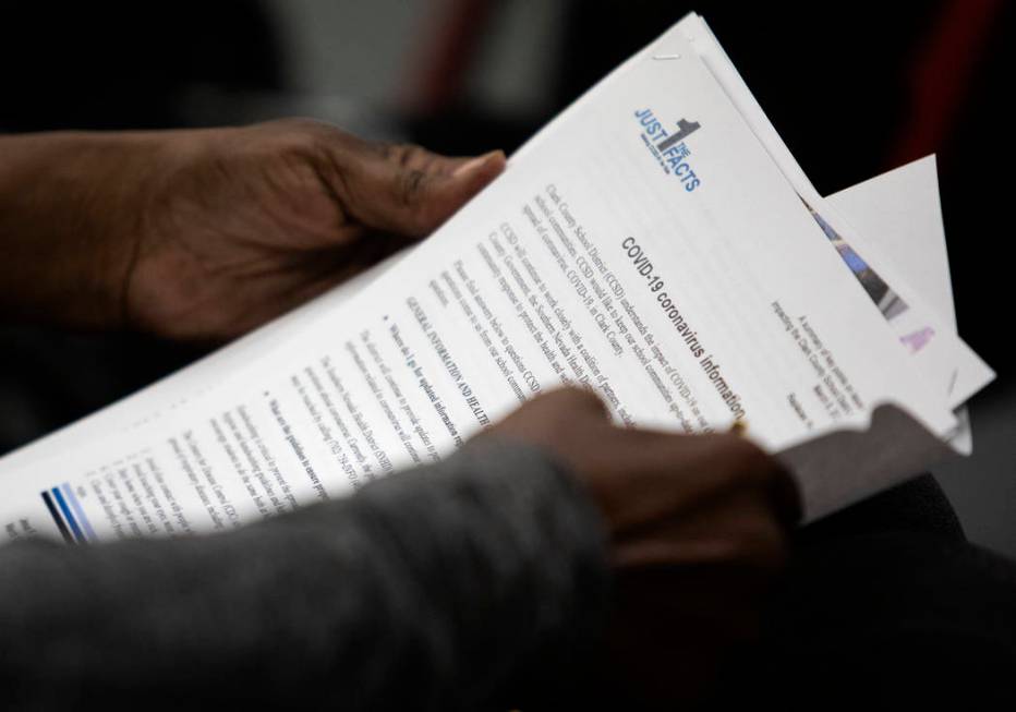 A community member reads information on COVID-19 during a Clark County School District Board of ...