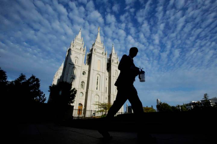 A man walks past the Salt Lake Temple, a temple of The Church of Jesus Christ of Latter-day Sai ...
