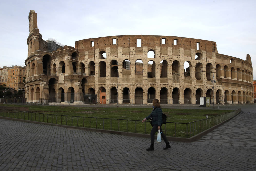 A woman walks in front of Rome's ancient Colosseum in the afternoon of Thursday, March 12, 2020 ...