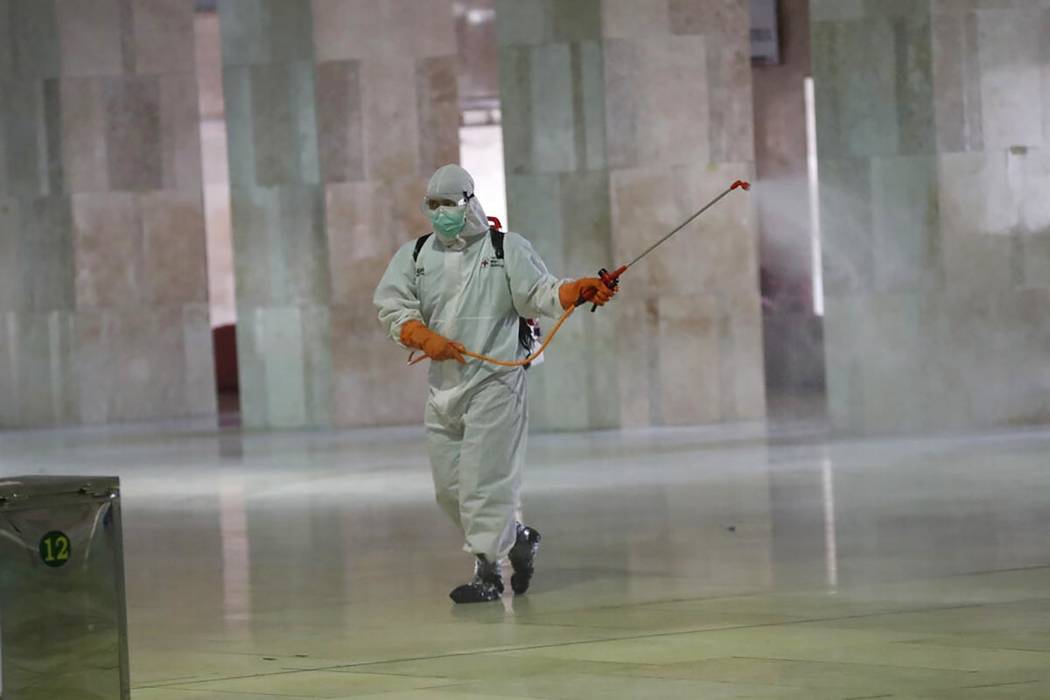 An official sprays disinfectant in the wake of the new coronavirus outbreak at Istiglal mosque ...