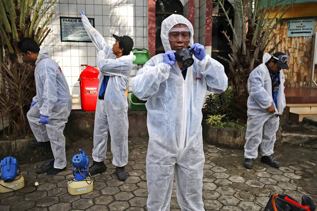 Health officials don their protective suits as they prepare to disinfect a mosque ahead of the ...