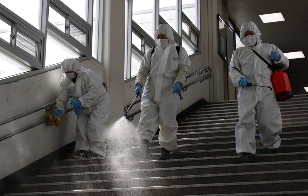 Workers wearing protective gears disinfect as a precaution against the new coronavirus at the s ...
