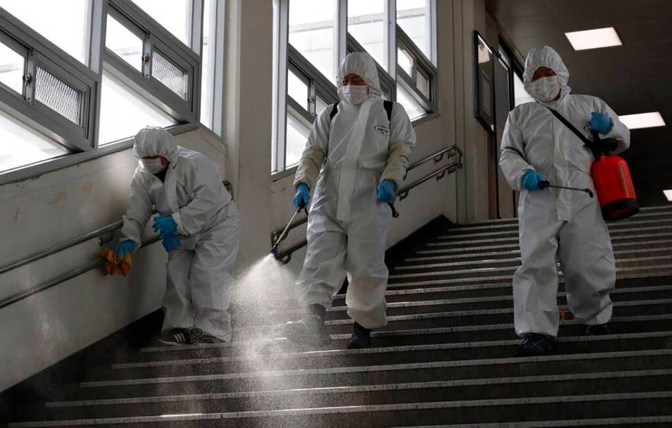 Workers wearing protective gears disinfect as a precaution against the new coronavirus at the s ...