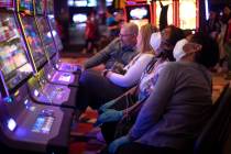 Gamblers wear masks and gloves in the midst of the coronavirus pandemic at Planet Hollywood on ...