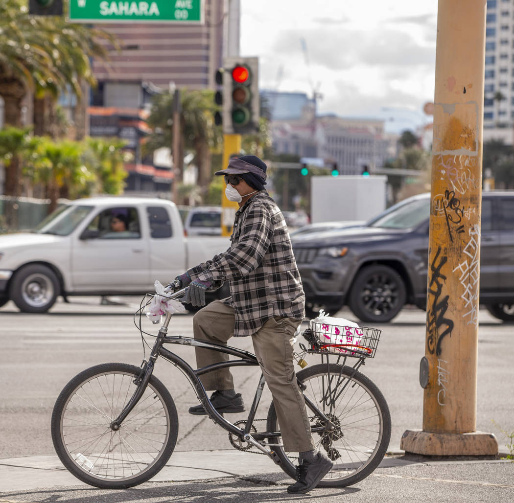 A man bicycles wearing a face mask along West Sahara Avenue on Saturday, March 14, 2020 in Las ...