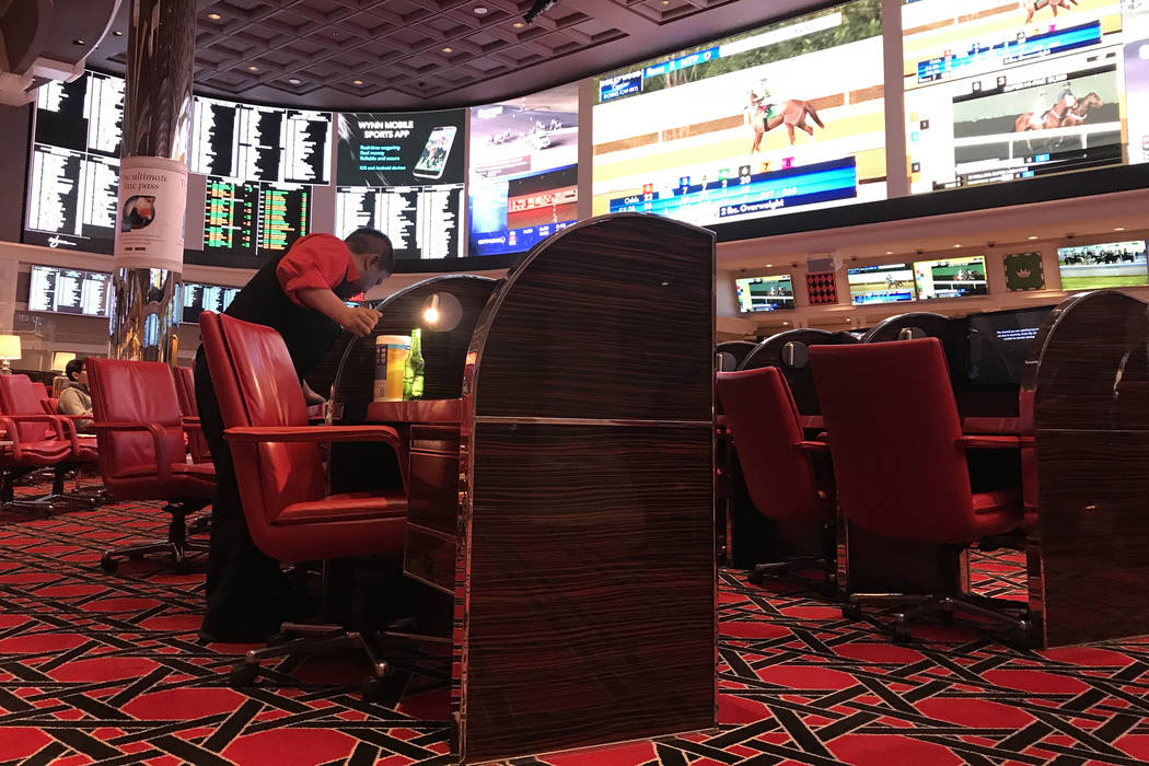 An employee wipes down chairs with Clorox wipes at Wynn Race & Sports Book on Friday, March ...
