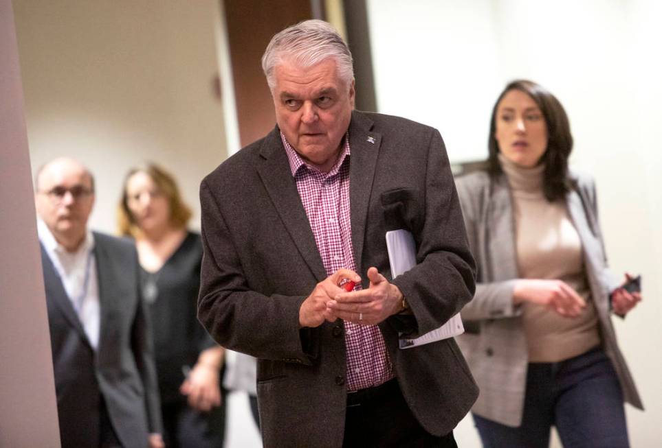Gov. Steve Sisolak uses hand sanitizer as he walks to the podium to give remarks on the COVID-1 ...
