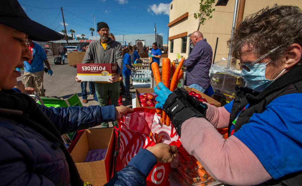 Christina Bailey, right, helps distribute carrots to those in need at SHARE Village Las Vegas o ...