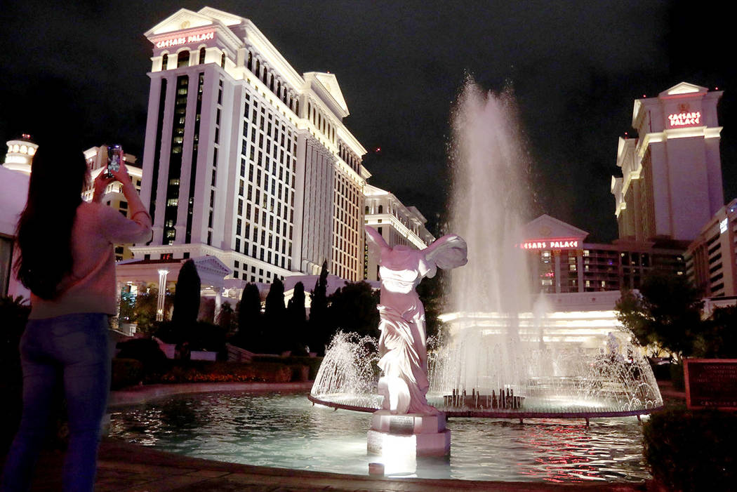 A woman takes a photo of Caesars Palace in Las Vegas, Saturday, March 14, 2020. ((Ellen Schmidt ...