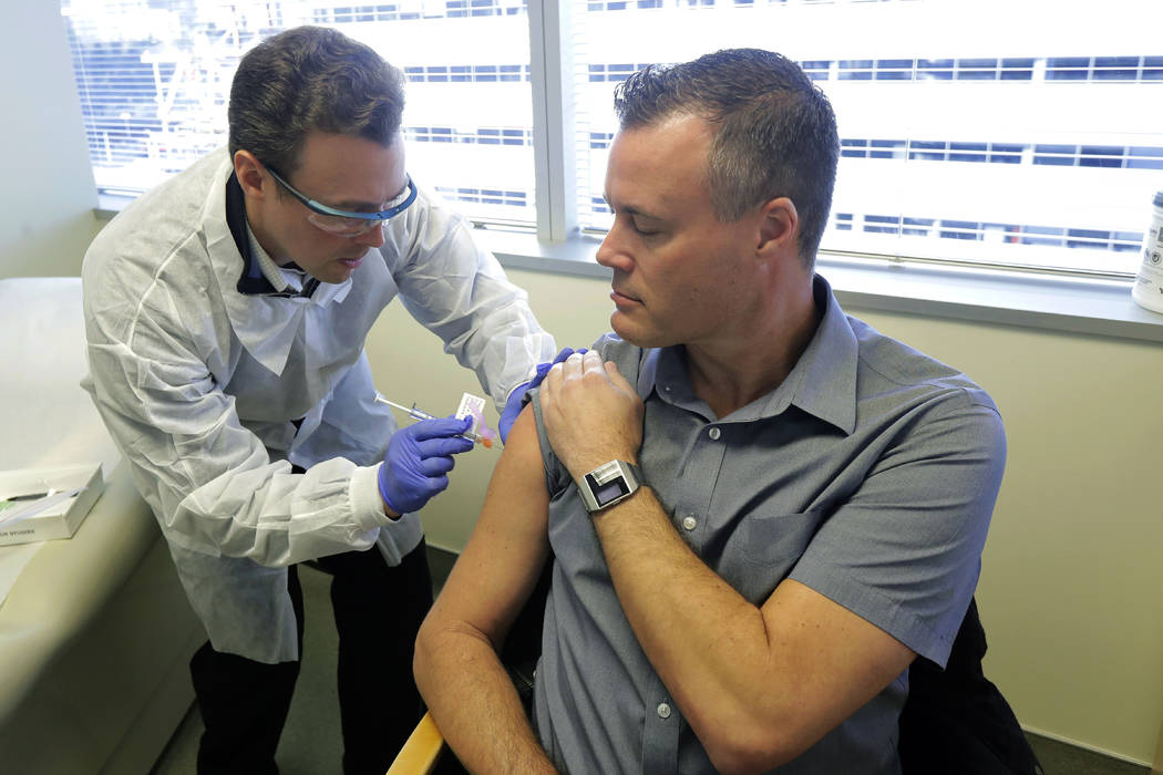 Pharmacist Michael Witte, left, gives Neal Browning, right, a shot in the first-stage safety st ...