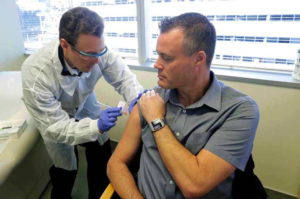 Pharmacist Michael Witte, left, gives Neal Browning, right, a shot in the first-stage safety st ...