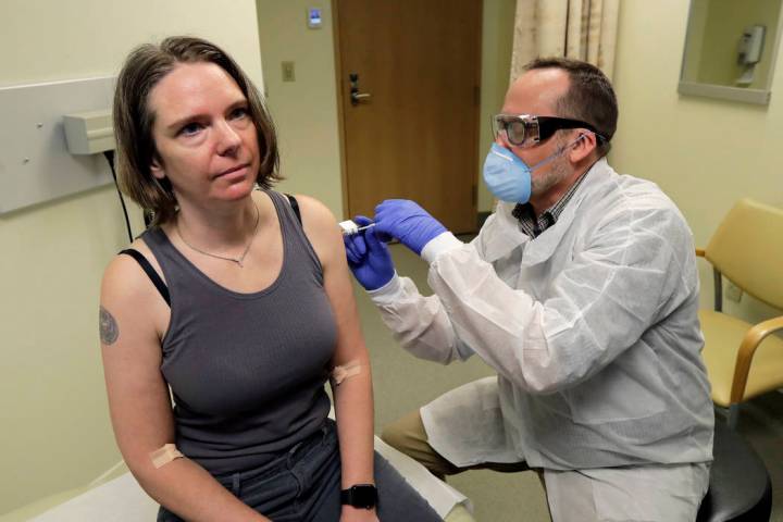 A pharmacist gives Jennifer Haller, left, the first shot in the first-stage safety study clinic ...