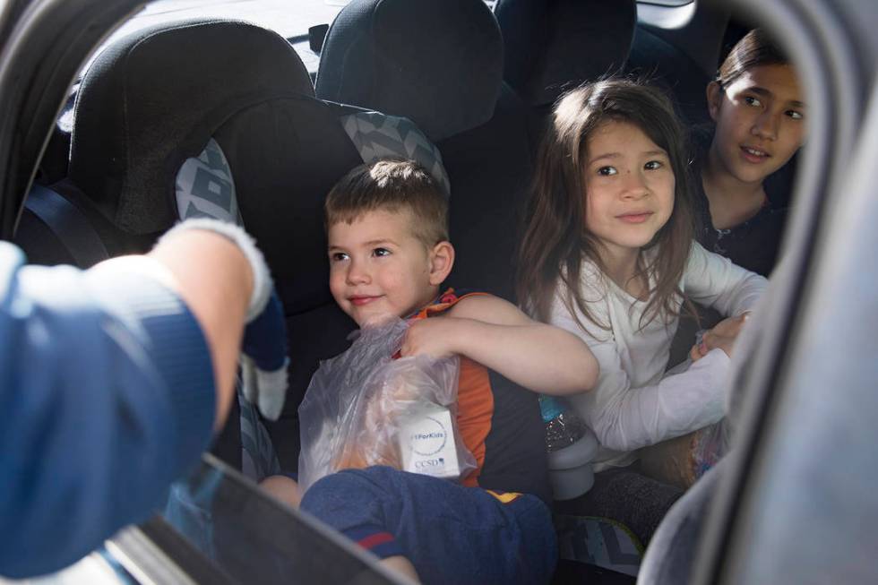 A Clark County School District employee hands packaged food to siblings Michael Randal, 3, left ...