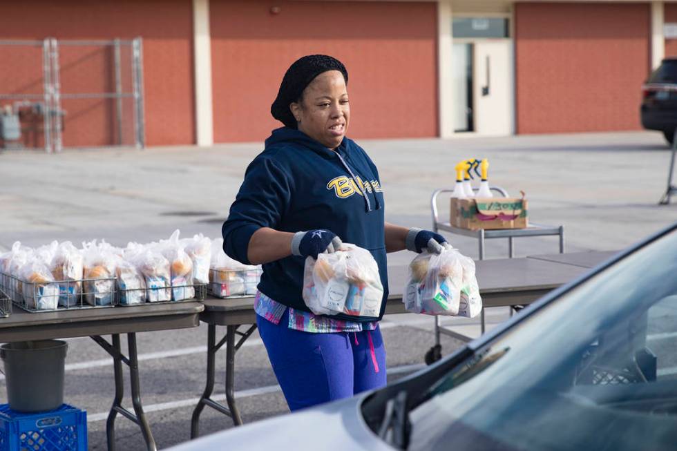 A Clark County School District employee hands out breakfast and lunch packages to families at C ...