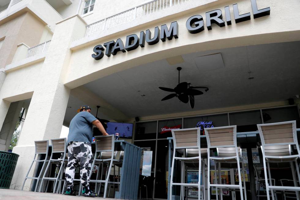 A person stands near empty seats at Stadium Grill, Monday, March 16, 2020, in Jupiter, Fla. The ...