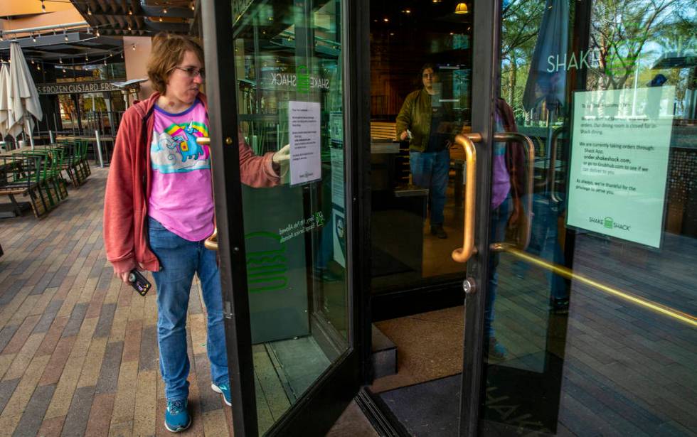 A Shake Shack customer reads the sign outside stating just carryout for the time being at Downt ...