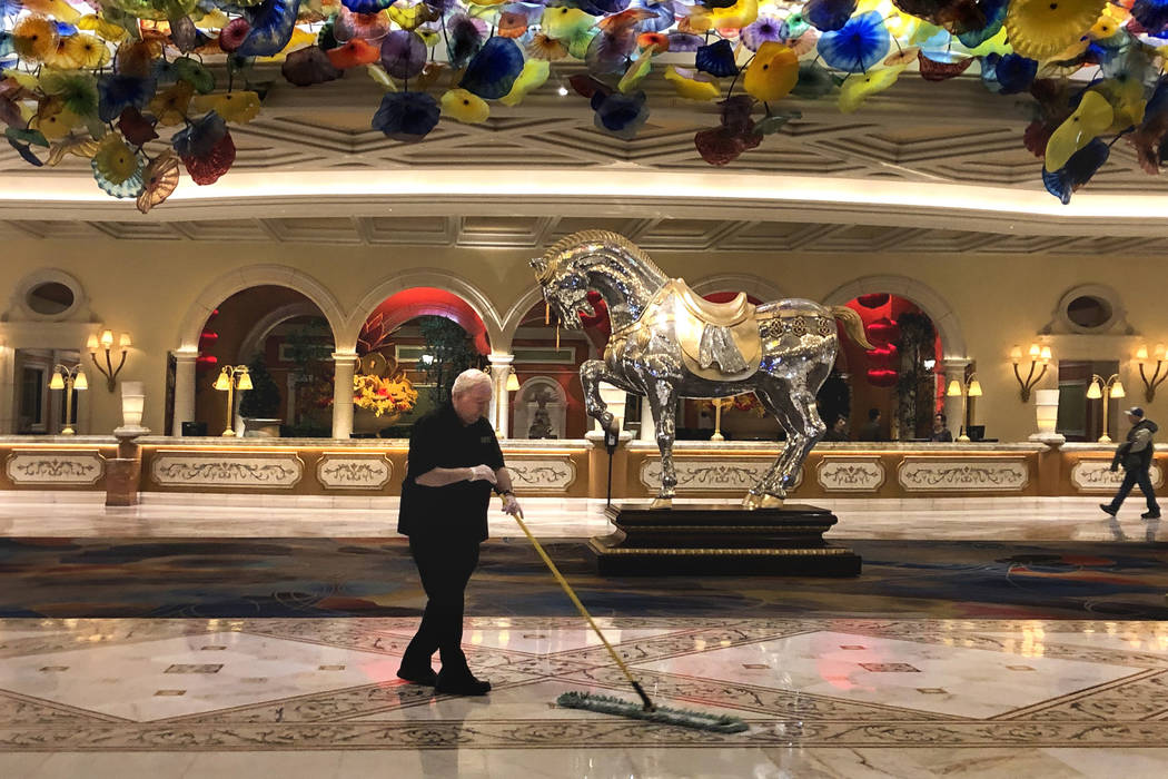 A janitor sweeps the Bellagio atrium as the casino prepares to temporarily shut down operations ...