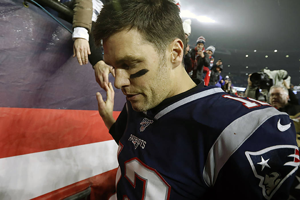 New England Patriots quarterback Tom Brady shakes hands with a fan as he leaves the field after ...