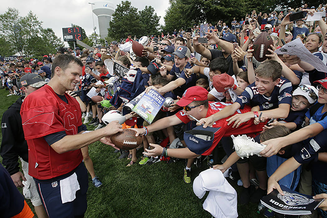 New England Patriots' Tom Brady, left, signs autographs for fans at NFL football training camp ...