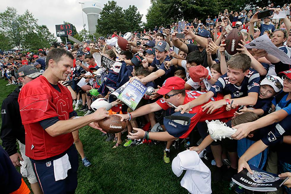 New England Patriots' Tom Brady, left, signs autographs for fans at NFL football training camp ...