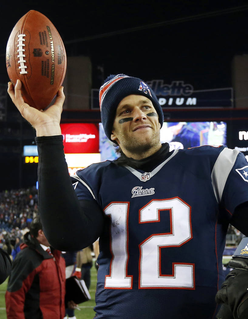 New England Patriots quarterback Tom Brady holds up the game ball after an NFL divisional playo ...